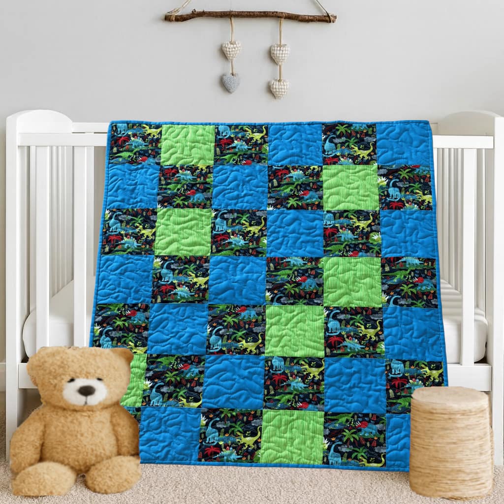Dinosaur Dreams Baby Quilt on white crib with bear
