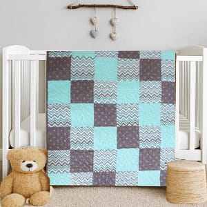 Coastal Calm Baby Quilt draped on white quilt with bear